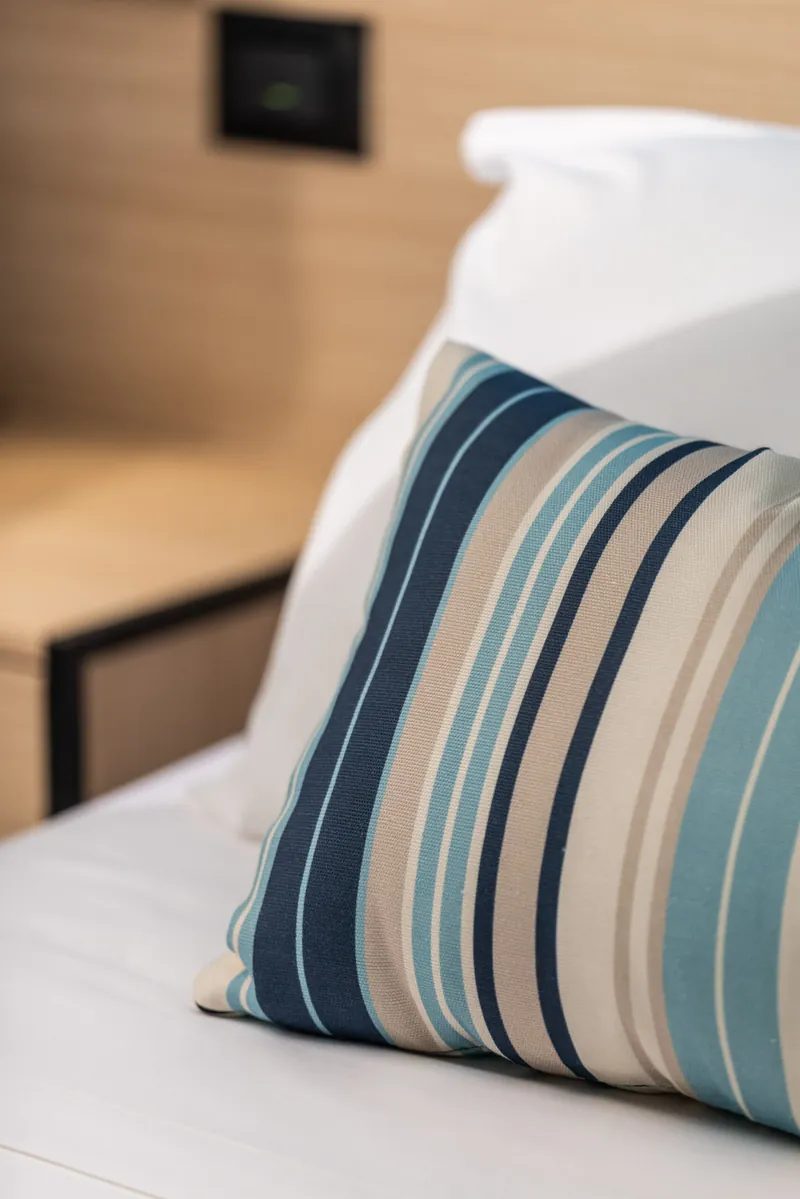 Cuscino a righe blu e color sabbia sul letto
