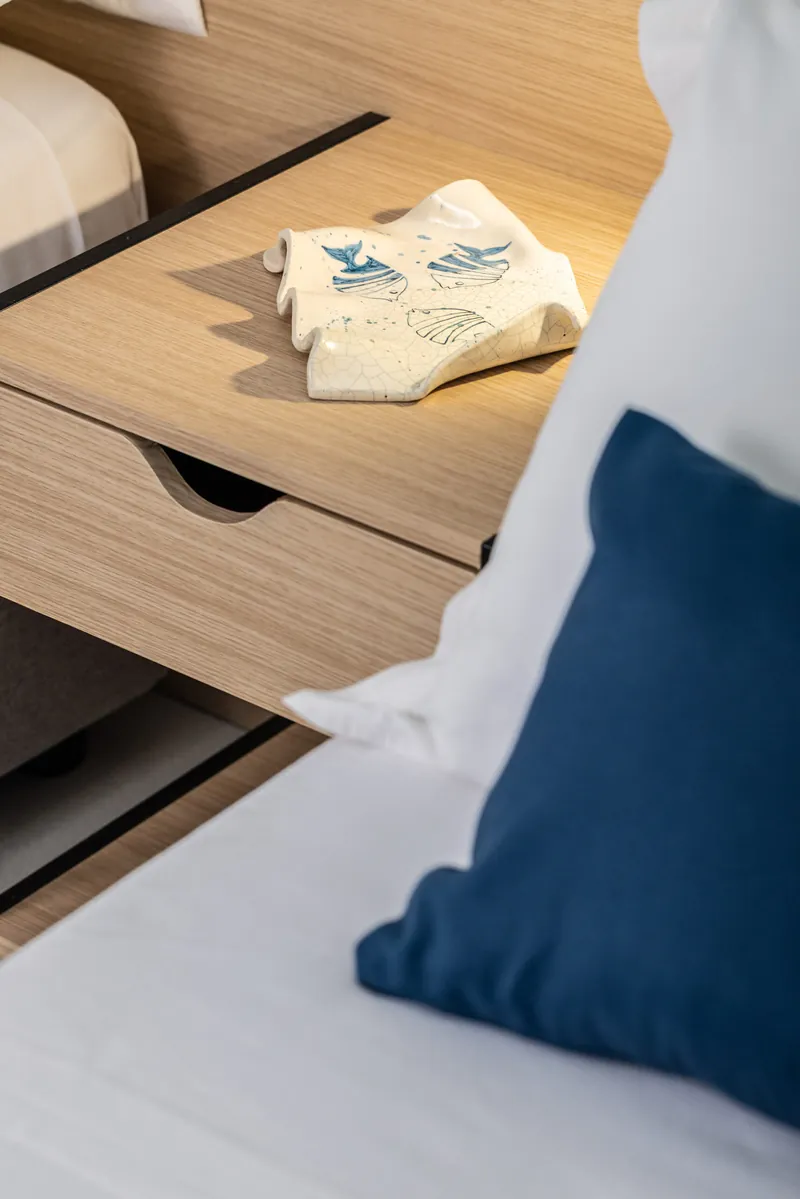 Comodino in legno con kit di cortesia accanto a un cuscino blu