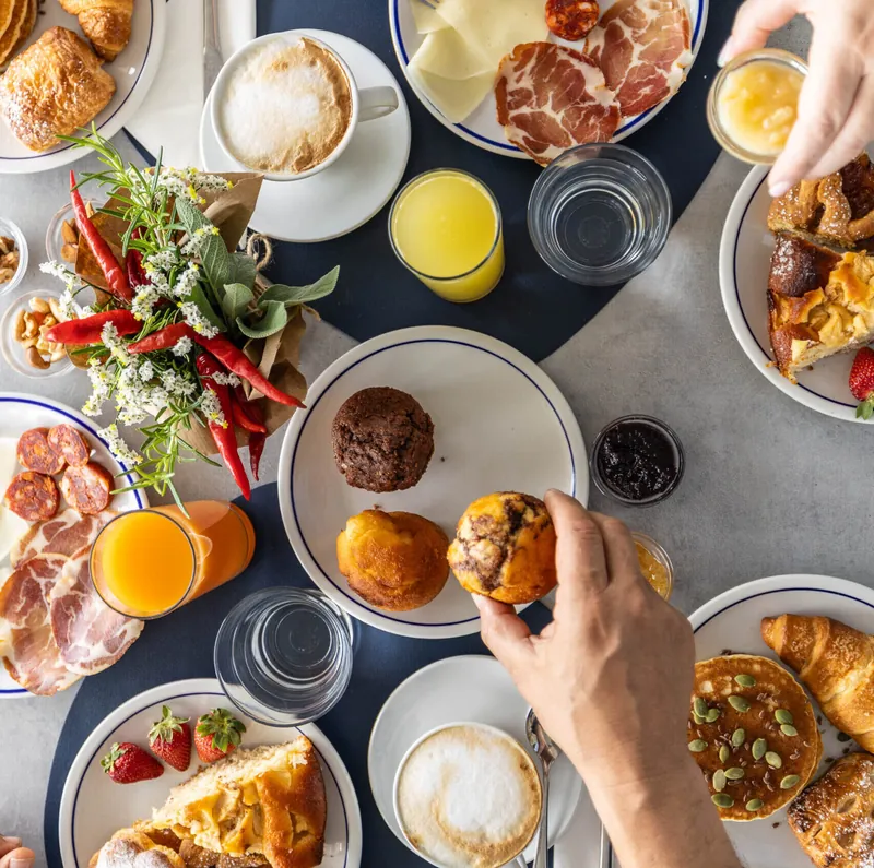 Colazione vista dall'alto con cornetti, cappuccini, salumi e spremute