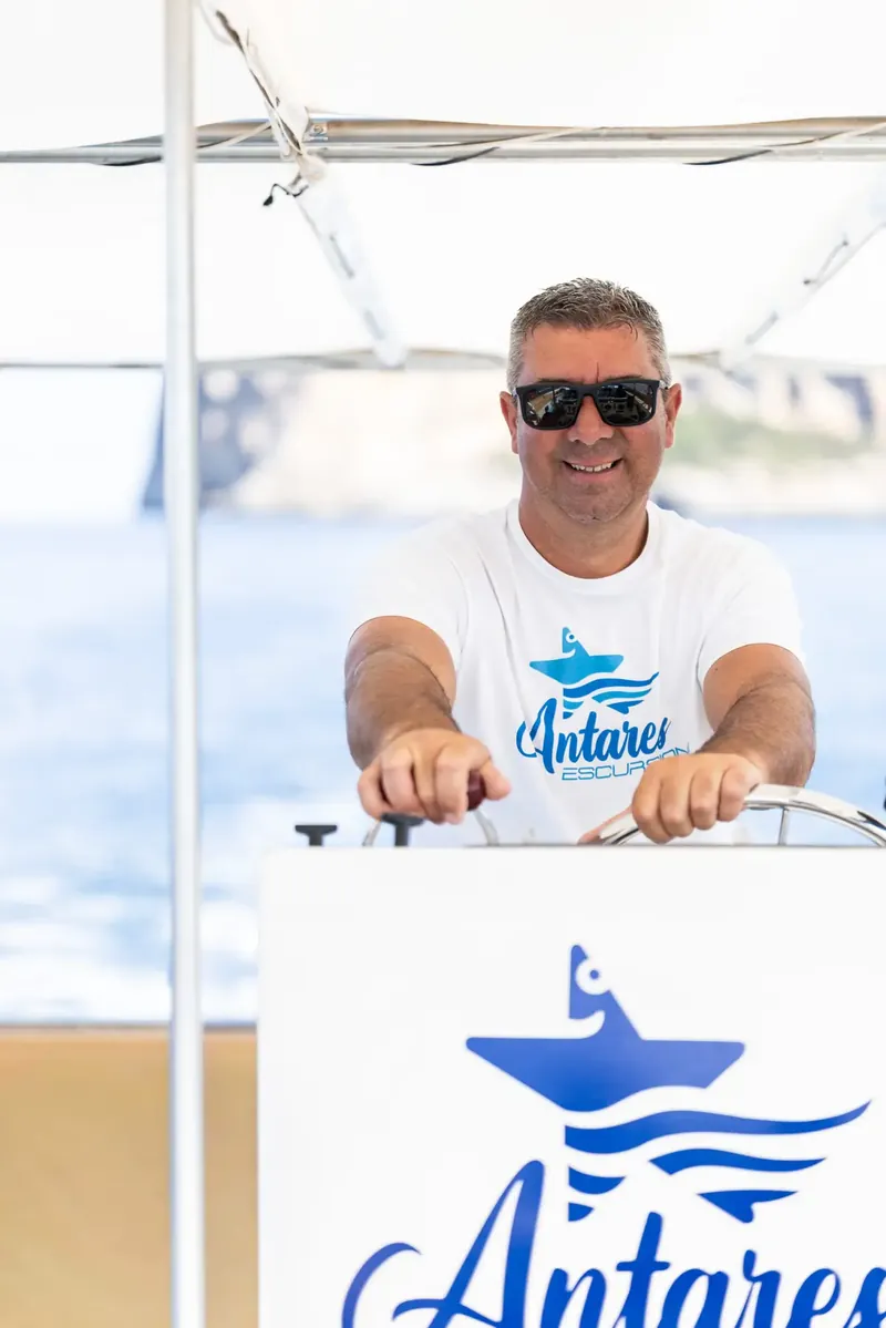 Skipper sorridente al timone della barca Antares